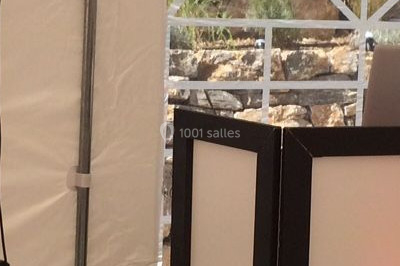 Salle de réception décorée avec des lumières violettes, tables dressées et écran affichant des prénoms.