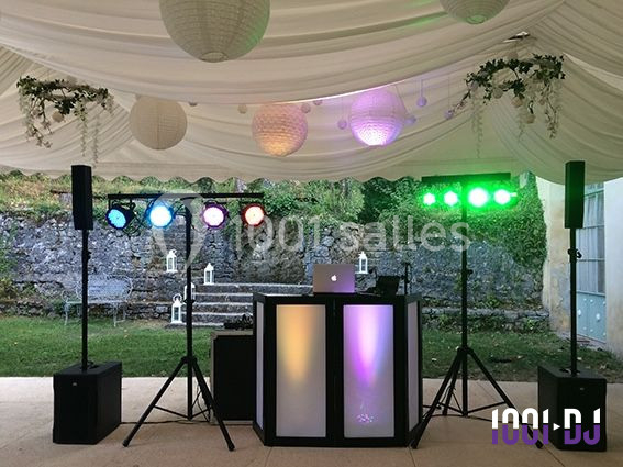 Installation de matériel de sonorisation et éclairage coloré sous une tente blanche pour un événement en extérieur.