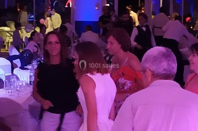 Salle de réception décorée avec des lumières violettes, tables dressées et écran affichant des prénoms.