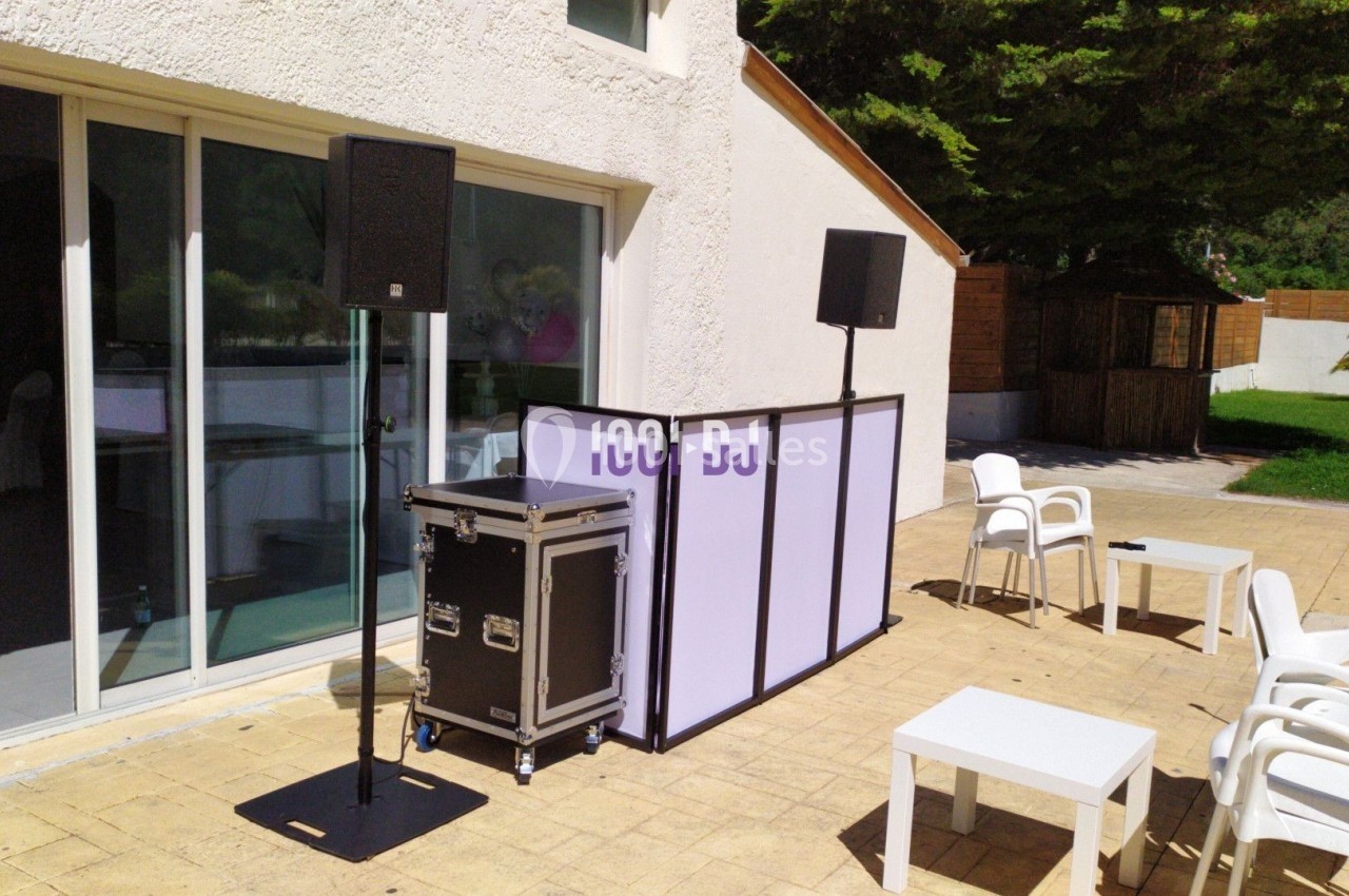 Installation de matériel de sonorisation et éclairage sur une terrasse extérieure, avec tables et chaises blanches.
