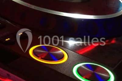 Platines DJ éclairées avec des boutons lumineux colorés et des reflets métalliques dans une ambiance sombre.