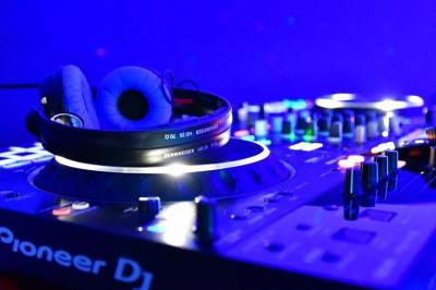 Table de mixage DJ avec platines et commandes lumineuses, installée dans un espace intérieur avec des tables en arrière-plan.