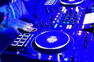 Table de mixage DJ avec platines et commandes lumineuses, installée dans un espace intérieur avec des tables en arrière-plan.