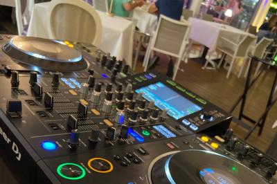 Table de mixage DJ avec platines et commandes lumineuses, installée dans un espace intérieur avec des tables en arrière-plan.