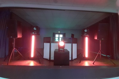 Équipement de sonorisation et éclairage installé dans une salle, comprenant enceintes, projecteurs et table de mixage.