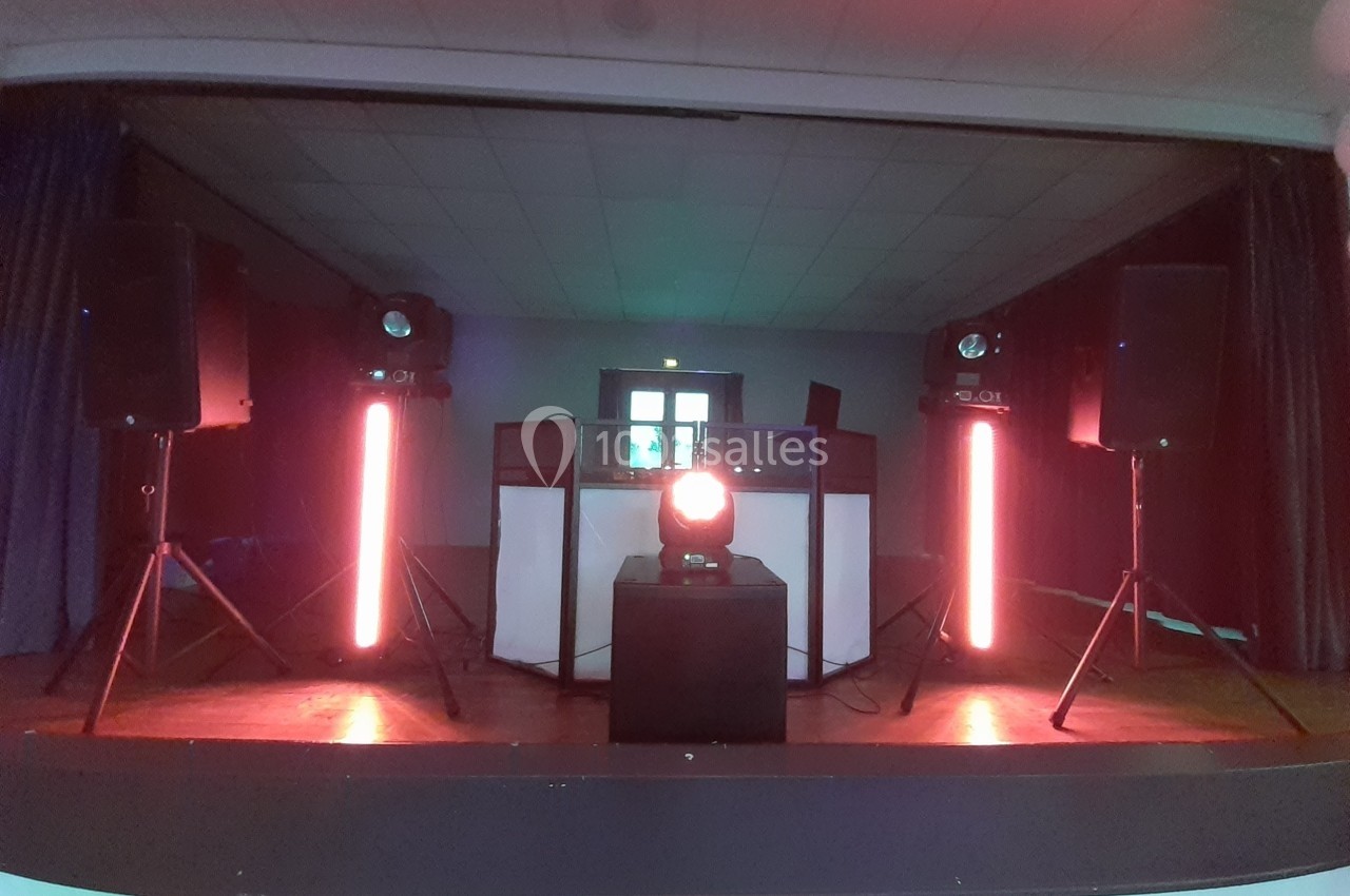 Équipement de sonorisation et éclairage avec projecteurs rouges installés sur une scène dans une salle sombre.