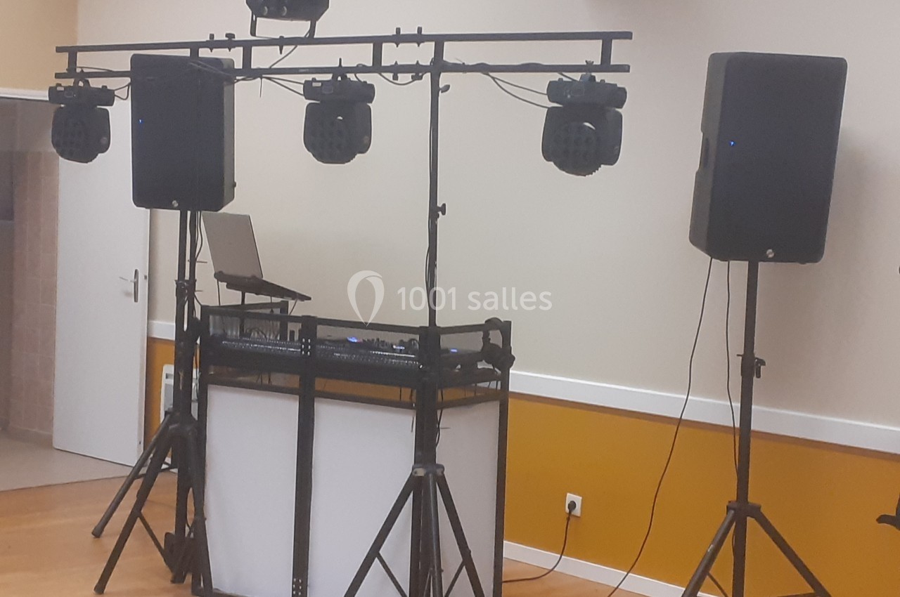 Équipement de sonorisation et éclairage installé dans une salle, comprenant enceintes, projecteurs et table de mixage.