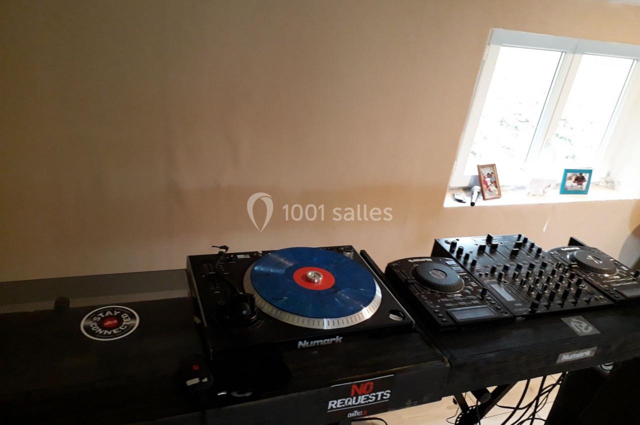 Deux platines et une table de mixage installées sur un support dans une pièce lumineuse avec un mur beige.