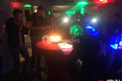 Des personnes dansent sous des lumières colorées dans une ambiance festive et tamisée.