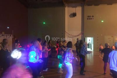 Des personnes dansent sous des lumières colorées dans une ambiance festive et tamisée.