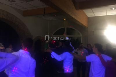 Des personnes dansent sous des lumières colorées dans une ambiance festive et tamisée.