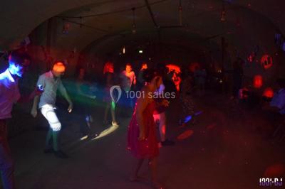 Des personnes dansent sous des lumières colorées dans une ambiance festive et tamisée.