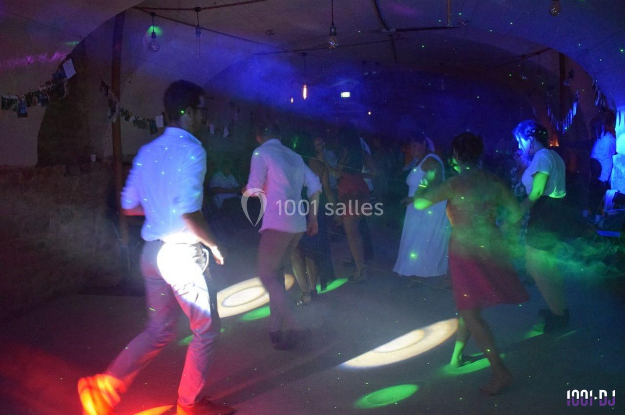 Des personnes dansent sous des lumières colorées dans une ambiance festive et tamisée.