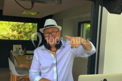 Personnes dansant sous des lumières colorées lors d'une soirée animée par un DJ dans une salle en pierre.