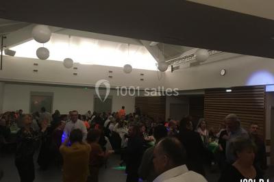 Personnes dansant sous des lumières colorées lors d'une soirée animée par un DJ dans une salle en pierre.