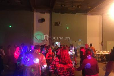 Personnes dansant sous des lumières colorées lors d'une soirée animée par un DJ dans une salle en pierre.