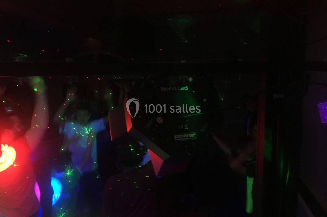 Personnes dansant dans une ambiance sombre avec des lumières colorées et des effets laser.