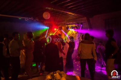Des personnes dansent en ligne dans une salle décorée de ballons, avec des tables dressées et des convives en arrière-plan.