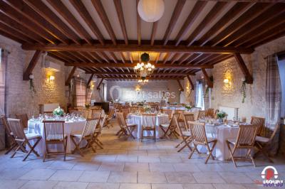 Des personnes dansent en ligne dans une salle décorée de ballons, avec des tables dressées et des convives en arrière-plan.