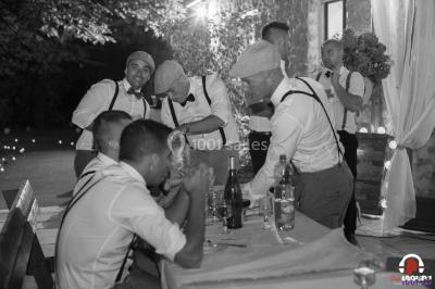 Des personnes dansent en ligne dans une salle décorée de ballons, avec des tables dressées et des convives en arrière-plan.