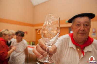 Des personnes dansent en ligne dans une salle décorée de ballons, avec des tables dressées et des convives en arrière-plan.