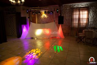 Des personnes dansent en ligne dans une salle décorée de ballons, avec des tables dressées et des convives en arrière-plan.