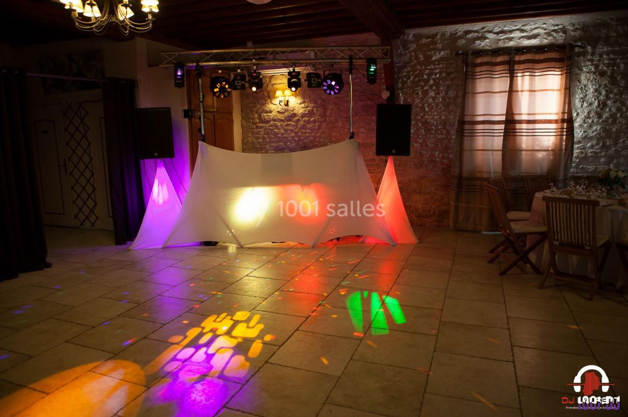 Installation de matériel de sonorisation et éclairage coloré dans une salle avec murs en pierre et rideaux beiges.