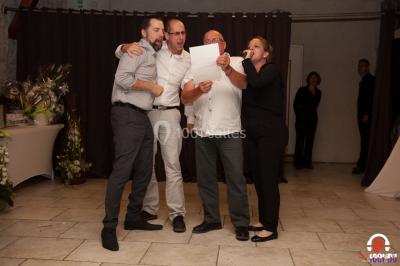 Des personnes dansent en ligne dans une salle décorée de ballons, avec des tables dressées et des convives en arrière-plan.