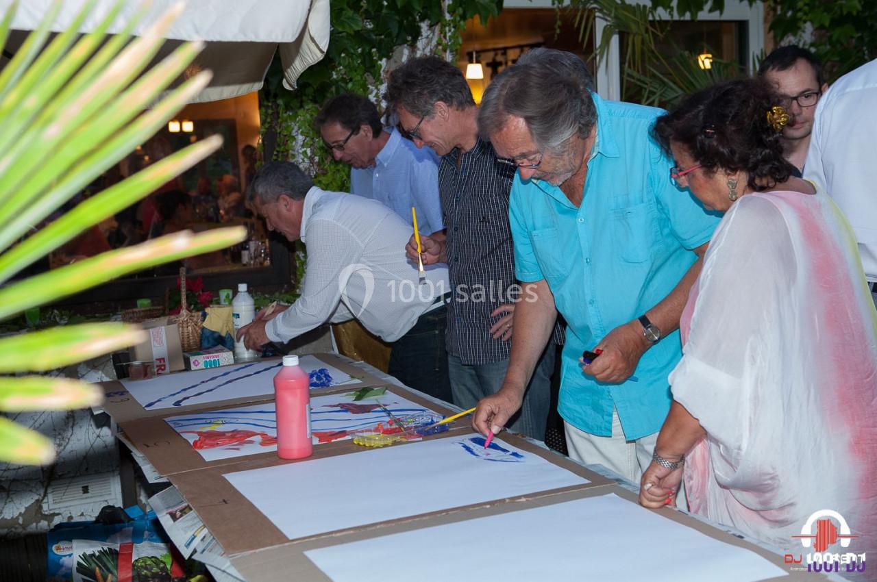 Des personnes participent à une activité artistique en plein air, peignant sur de grandes feuilles de papier.