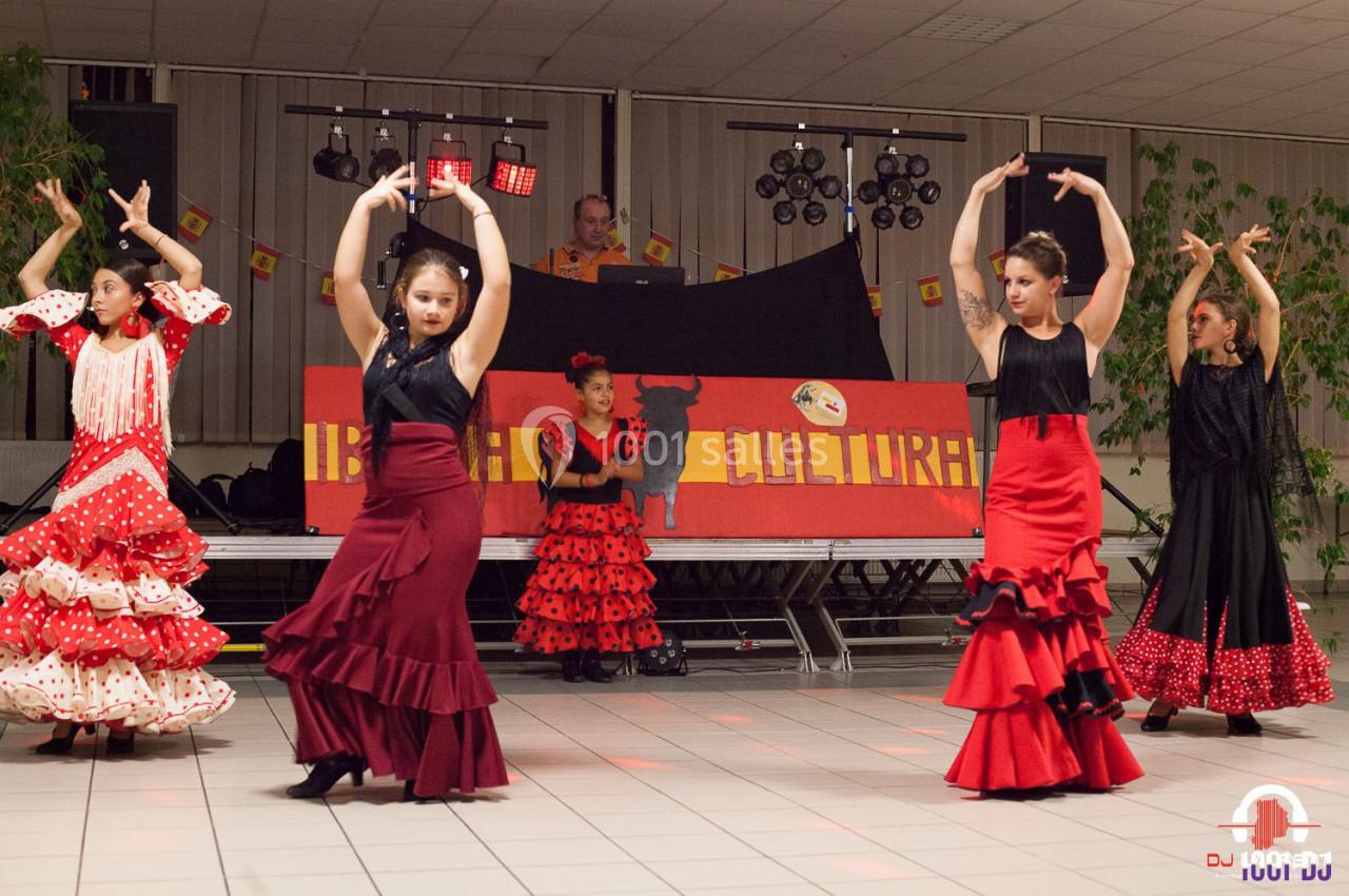 Des danseuses en tenue flamenco exécutent une chorégraphie sur une scène décorée aux couleurs espagnoles.