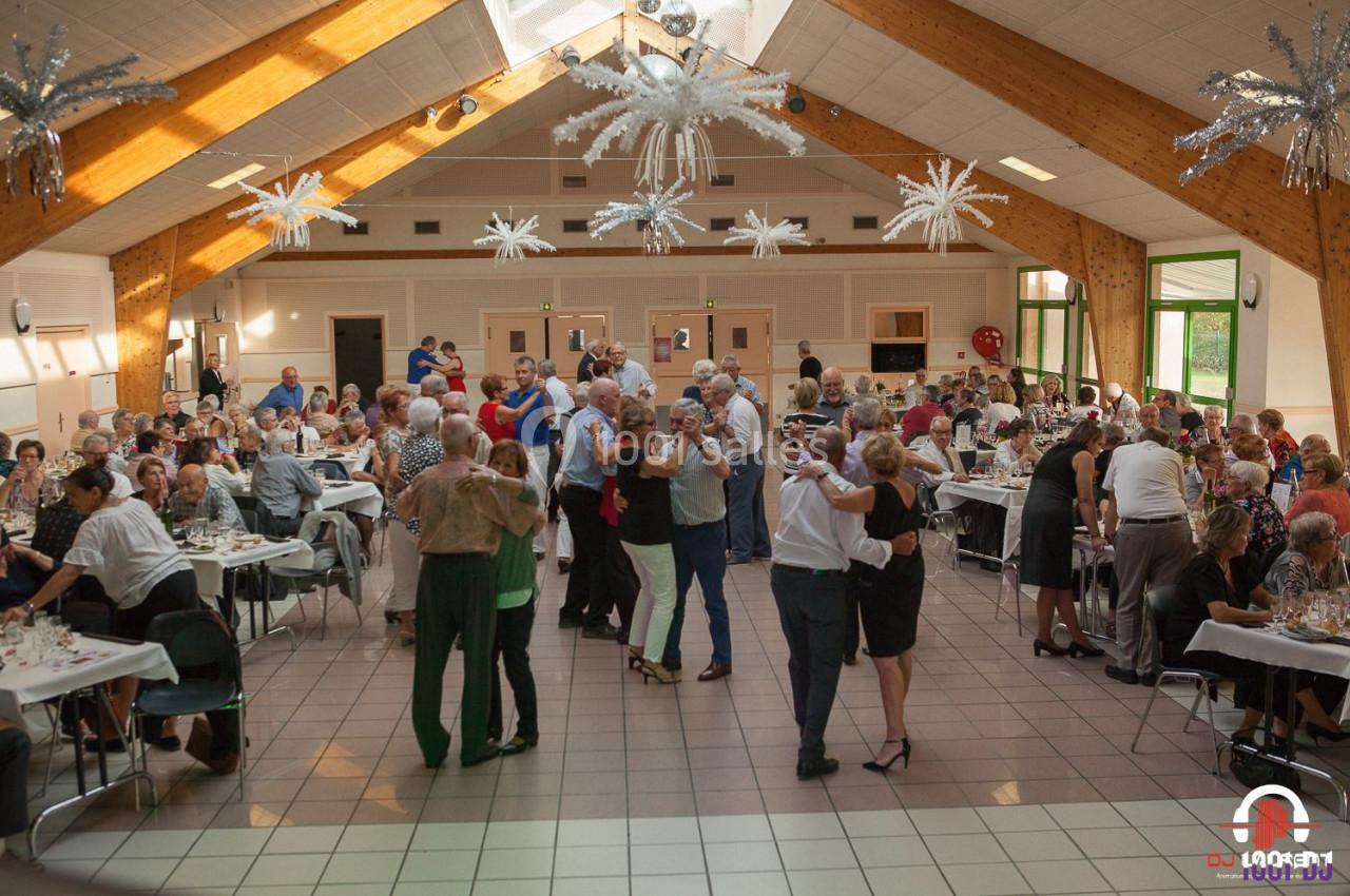 Des personnes dansent et dînent dans une grande salle lumineuse avec une décoration festive au plafond.