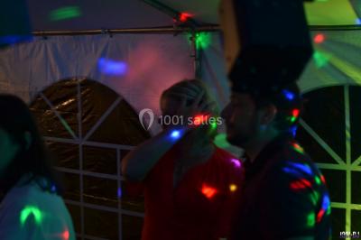 Des personnes dansent dans une ambiance festive avec des lumières colorées dans une salle sombre.