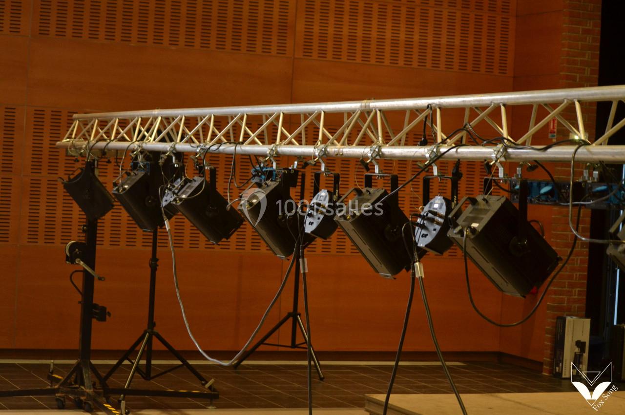 Projecteurs suspendus sur une structure métallique dans une salle avec murs en bois et sol sombre.