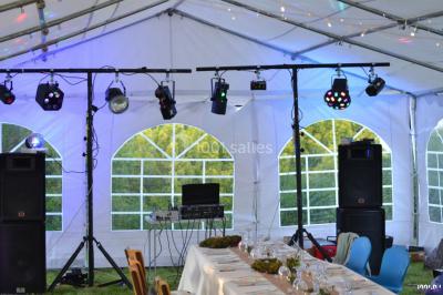 Salle polyvalente avec scène surélevée, rideaux bleus, écran blanc, tables et chaises disposées en avant-plan.