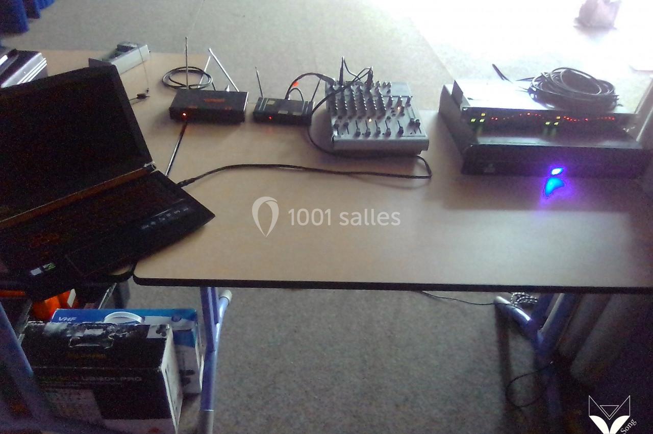 Matériel audio et informatique installé sur une table, comprenant un ordinateur portable, une console de mixage et des…
