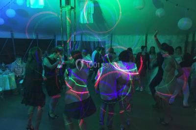 Personnes discutant dans une salle éclairée de lumières bleues, avec tables de buffet et décoration festive.