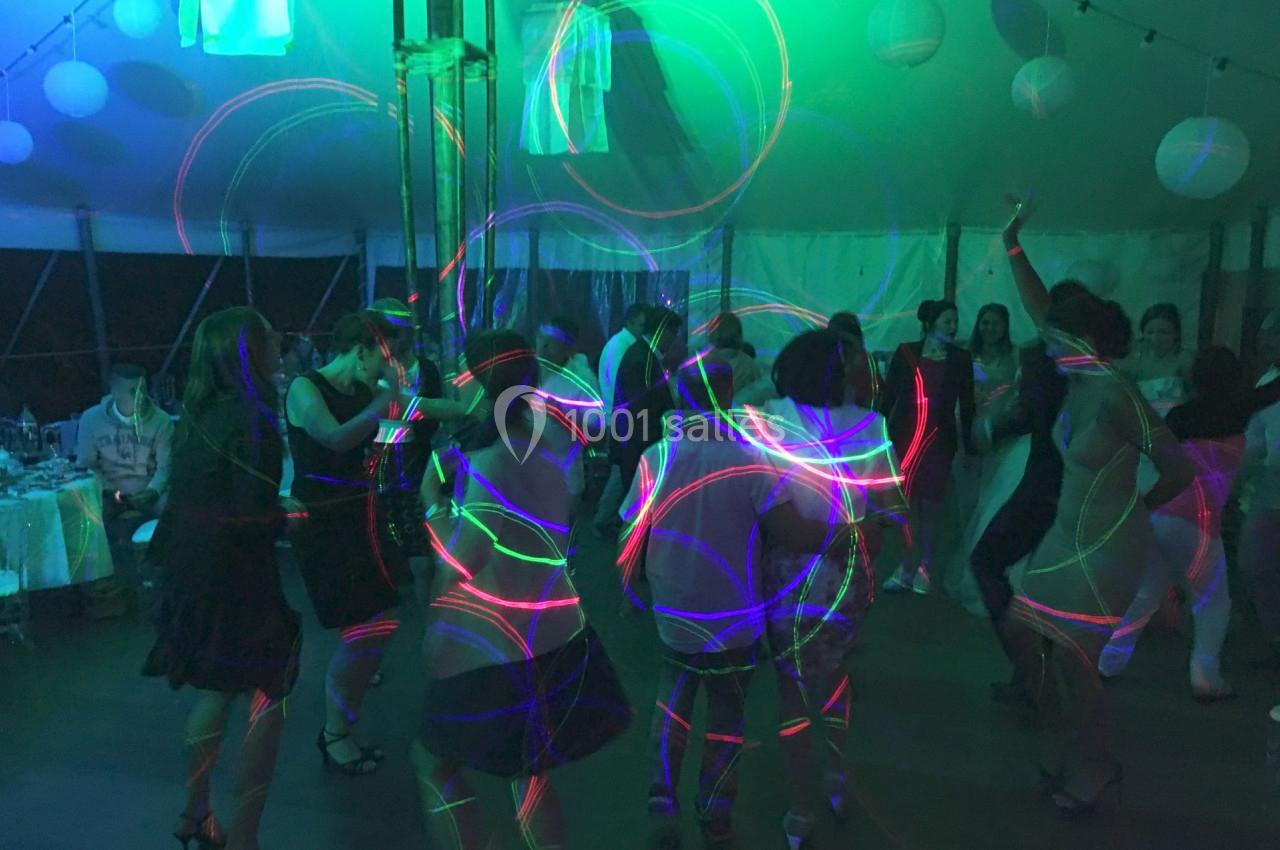 Personnes dansant sous des lumières colorées dans une ambiance festive sous une tente.