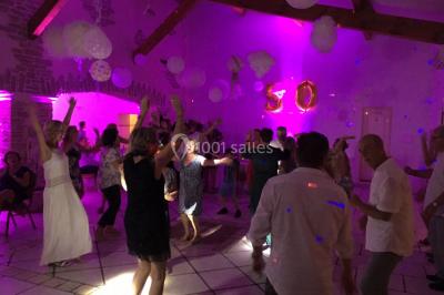 Personnes discutant dans une salle éclairée de lumières bleues, avec tables de buffet et décoration festive.