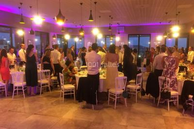 Personnes discutant dans une salle éclairée de lumières bleues, avec tables de buffet et décoration festive.