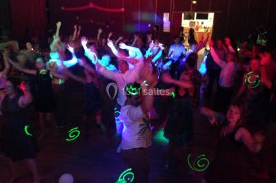 Personnes discutant dans une salle éclairée de lumières bleues, avec tables de buffet et décoration festive.