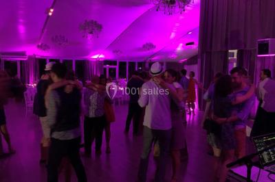 Personnes discutant dans une salle éclairée de lumières bleues, avec tables de buffet et décoration festive.