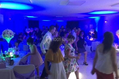 Personnes discutant dans une salle éclairée de lumières bleues, avec tables de buffet et décoration festive.