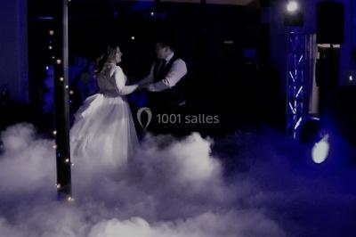 Personnes discutant dans une salle éclairée de lumières bleues, avec tables de buffet et décoration festive.