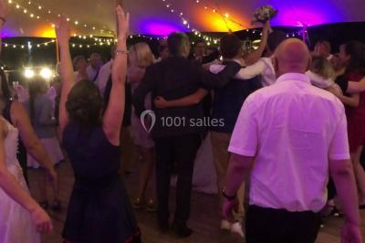Personnes discutant dans une salle éclairée de lumières bleues, avec tables de buffet et décoration festive.