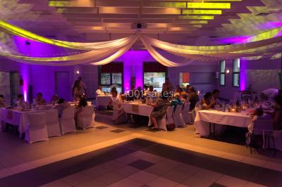 Personnes discutant dans une salle éclairée de lumières bleues, avec tables de buffet et décoration festive.