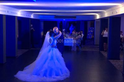 Personnes discutant dans une salle éclairée de lumières bleues, avec tables de buffet et décoration festive.