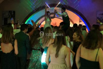 Personnes discutant dans une salle éclairée de lumières bleues, avec tables de buffet et décoration festive.