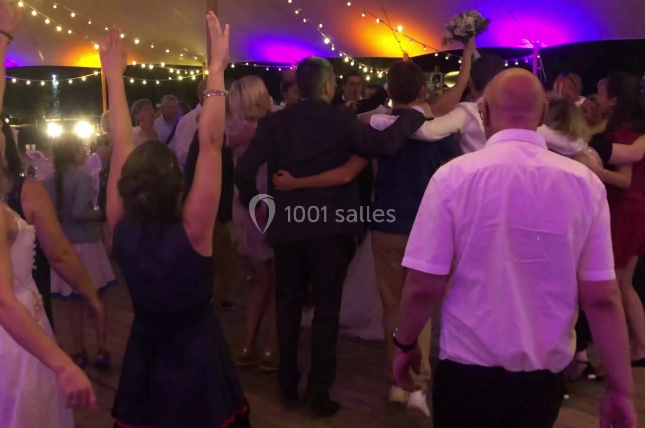 Groupe de personnes dansant sous une tente éclairée de guirlandes lumineuses colorées lors d'une fête.