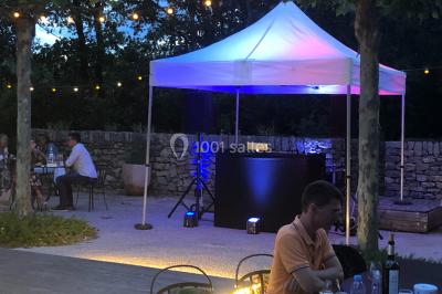 Salle de réception avec des invités assis à des tables, éclairée par des guirlandes lumineuses suspendues.