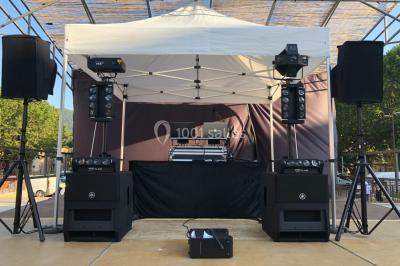 Salle de réception avec des invités assis à des tables, éclairée par des guirlandes lumineuses suspendues.